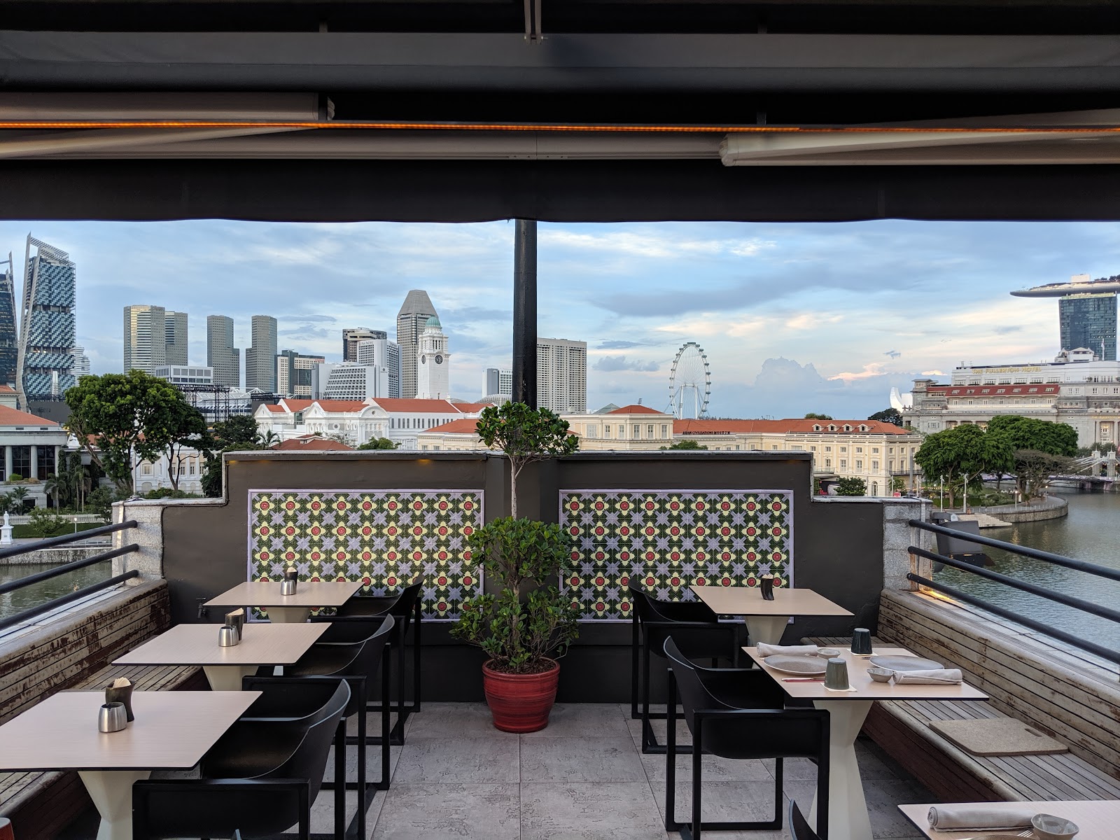 A Singapore rooftop dining room with the Marina Bay skyline through floor-to-ceiling glass