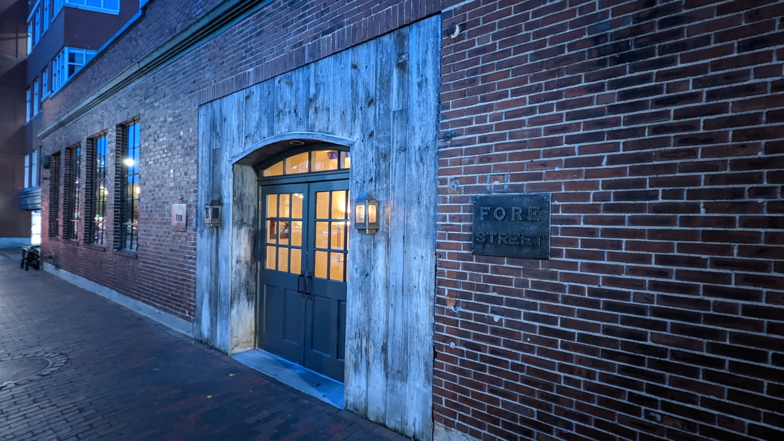An open wood-fired kitchen in a Portland, Maine Old Port dining room set for a business dinner