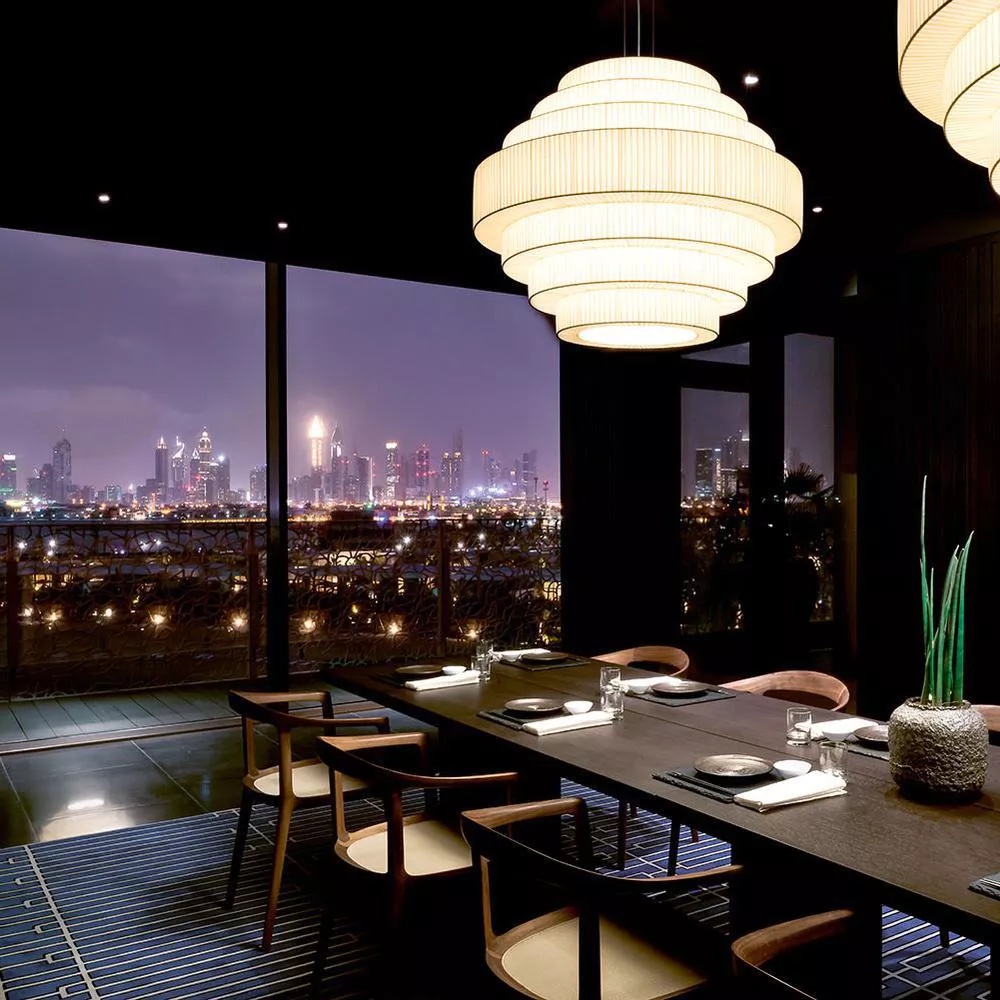 A chef plating across an intimate omakase counter in a Dubai restaurant