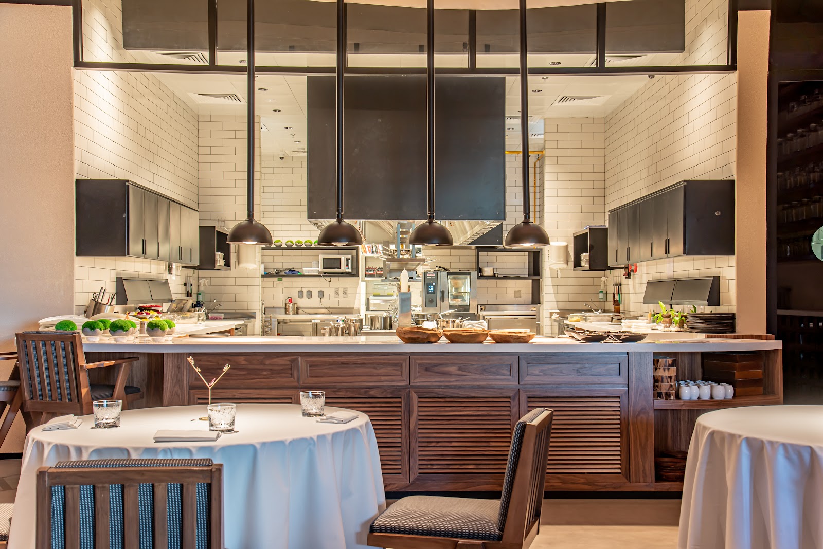 A chef plating at a counter in front of seated diners at a Dubai chef's table