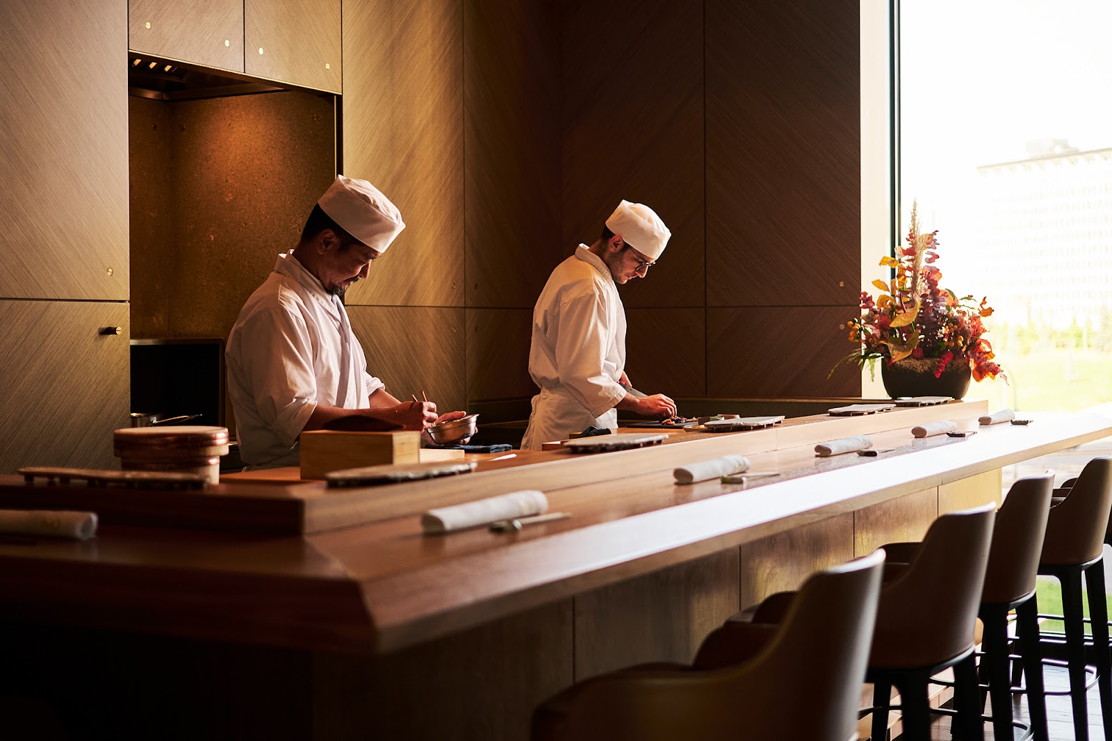 A chef plating a course at an omakase counter in Milan