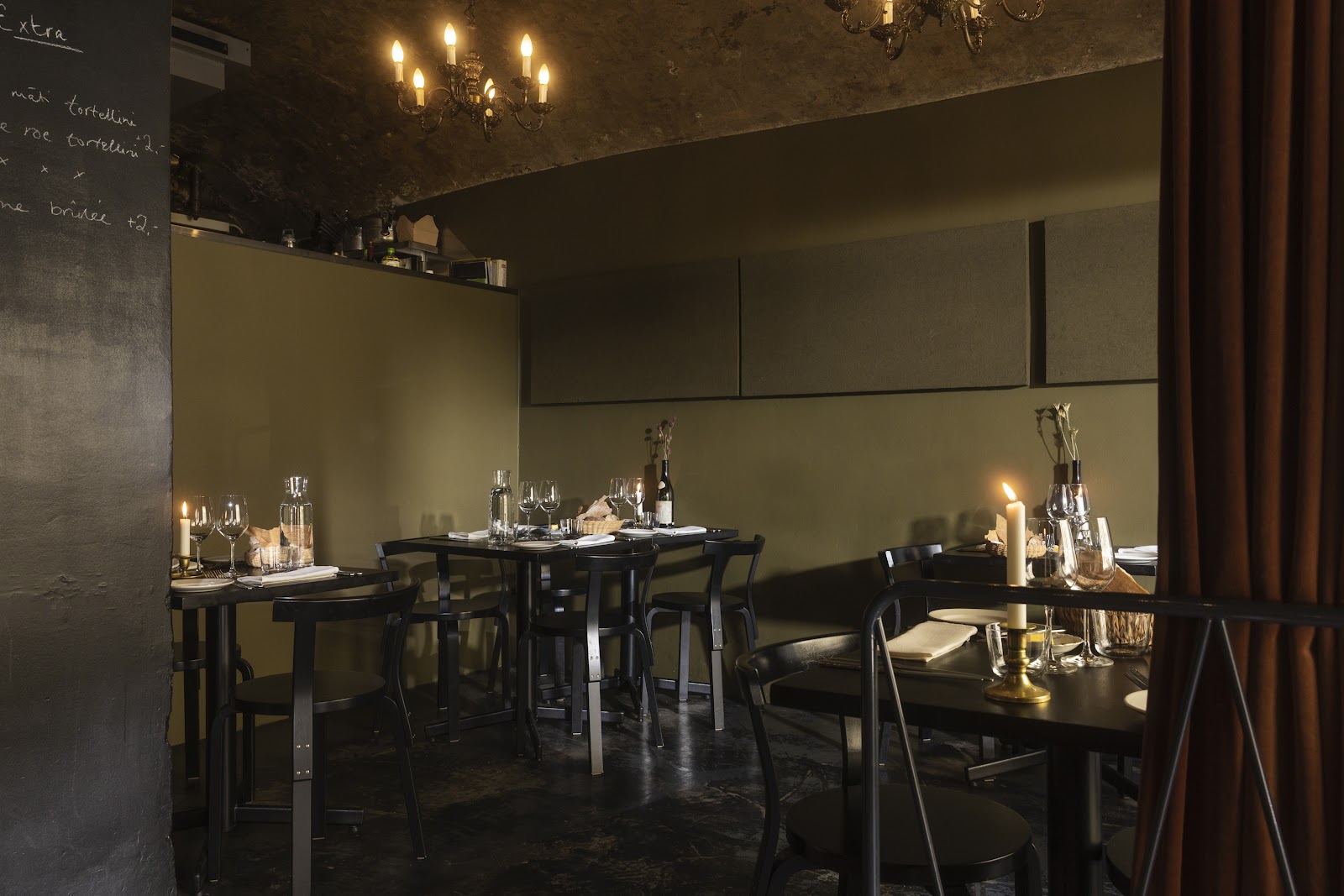 A candle-lit two-top set for a first date in a warm, low-lit Helsinki dining room