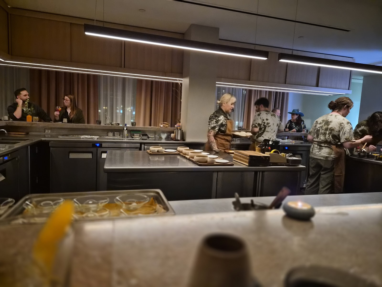Diners seated at a chef's counter watching cooks plate at a Nashville restaurant